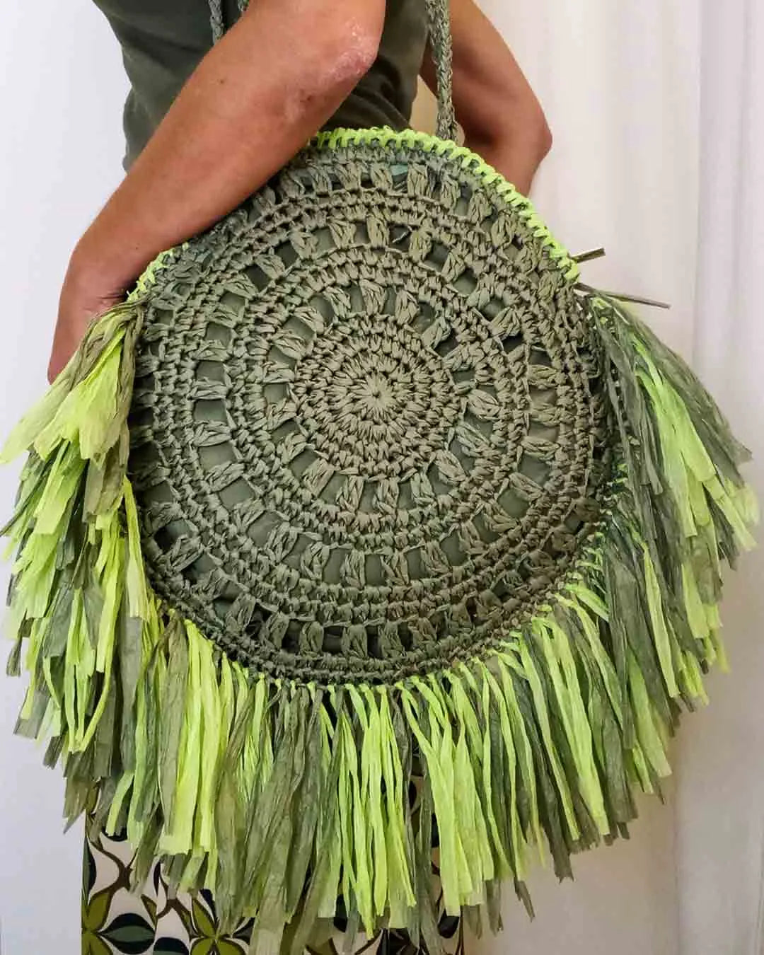 Borsa tonda con frange Verde è un accessorio che ti farà sentire esclusiva. Lavorata a uncinetto e decorata con frange in Rafia colorata di due tonalità di verde